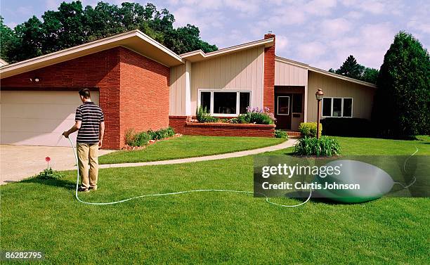 man watering yard with kinked garden hose - garden hose stock pictures, royalty-free photos & images