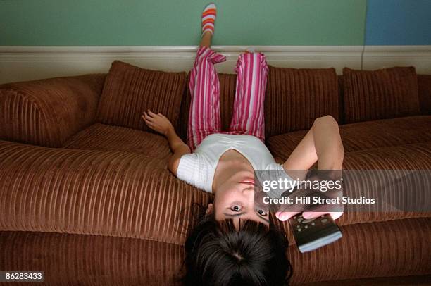 girl watching television upside down - lying on back girl on the sofa imagens e fotografias de stock