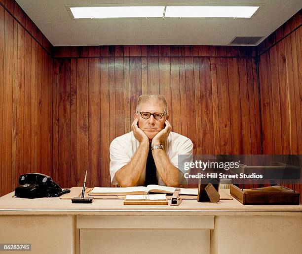 bored man sitting at desk - mühsal stock-fotos und bilder