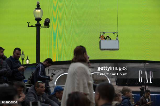 People mill around near the Piccadilly Circus billboard as it displays a test screen on October 18, 2017 in London, England. After nine months of...