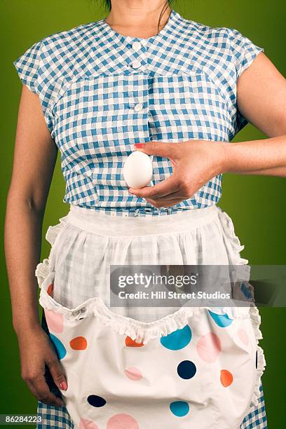 woman in an apron holding an egg - hill street studios bildbanksfoton och bilder