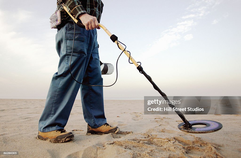 Man using metal detector at beach