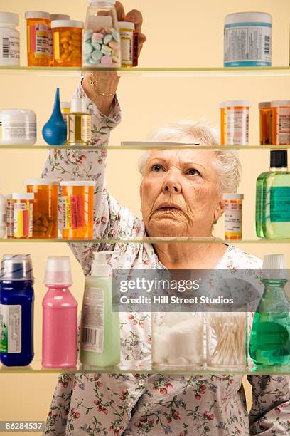 woman at medicine cabinet - bathroom cabinet stock pictures, royalty-free photos & images