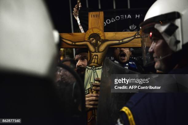 Members of orthodox religious organizations face anti-riot policemen as they demonstrate outside a theater, protesting against the play of Portuguese...
