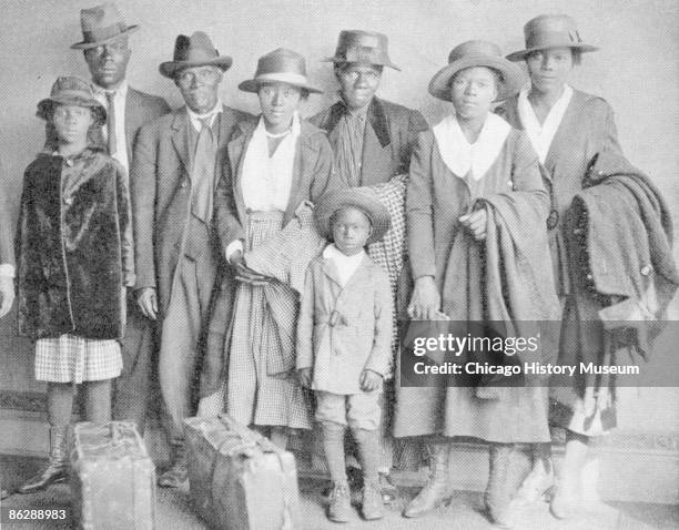 Photograph of African American men, women, and children who participated in the Great Migration to the north, with suitcases and luggage placed in...