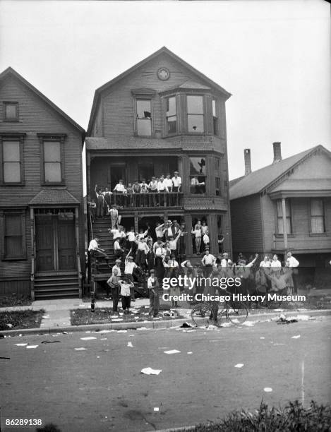 View of white children celebrating after having raided the home of African Americans during the race riots, Chicago, 1919. Note the broken windows...