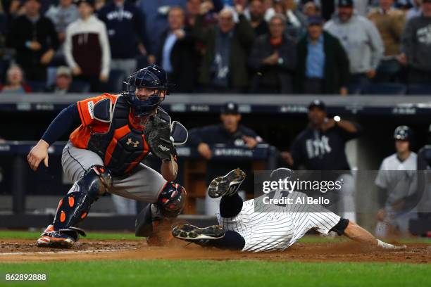 Brett Gardner of the New York Yankees slides in safely at home plate to score on a double by Aaron Judge against Brian McCann of the Houston Astros...