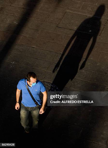 Man walks wearing a mask in the 5 de Mayo street, in Mexico City, on April 29, 2009. The World Health Organisation raised its flu alert to phase five...