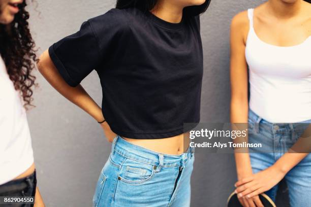 crop of teenage girls wearing jeans - naveltruitje stockfoto's en -beelden