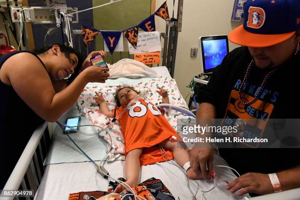 Tatiana Shibata, left, takes a picture of her son Ryker Christensen, as her husband Casey Christensen, right, prepares Ryker to go outside on his...