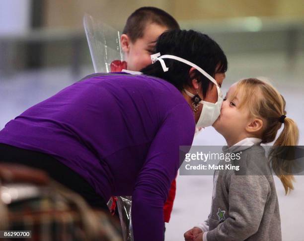 Women wearing a face mask kisses a young girl upon her arrival at Sydney International Airport on April 30, 2009 in Sydney, Australia. The World...