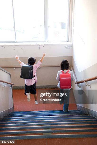 schoolboy and girl (8-9) going down staircase - 7 steps stockfoto's en -beelden