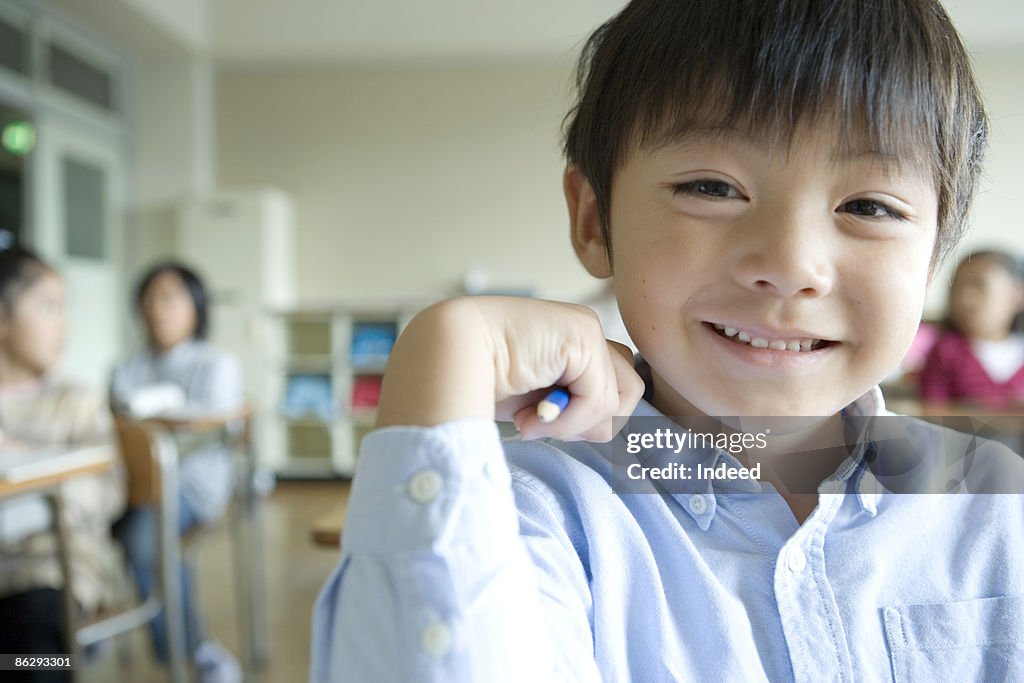 Schoolboy (6-7) smiling in classroom, portrait