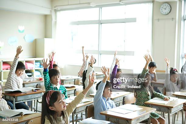 school children (6-11) raising hands - elementary school classroom stock pictures, royalty-free photos & images