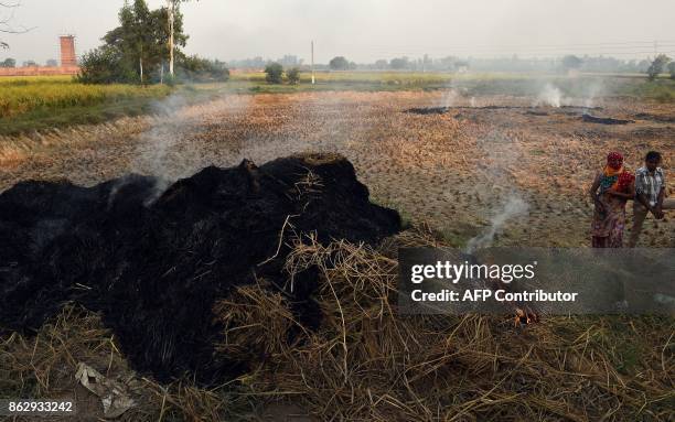 This photo taken on October 16, 2017 shows paddy crop stubble smouldering in a field in Sonipat in the northern Indian state of Haryana. As Hindus...