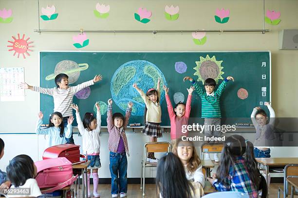 school children in classroom, raising arms - alleen kinderen stockfoto's en -beelden