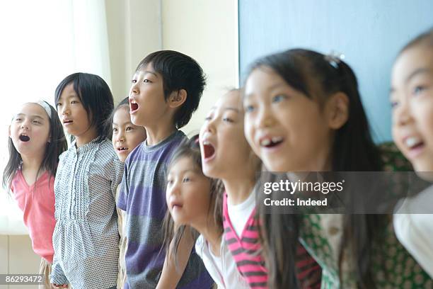 school children (8-9) singing in classroom - enfant chant classe photos et images de collection