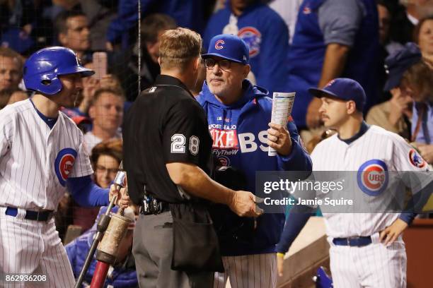 Manager Joe Maddon of the Chicago Cubs meets with umpire Jim Wolf in the sixth inning during game four of the National League Championship Series...