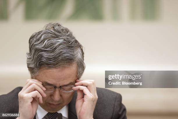 Zhou Xiaochuan, governor of the People's Bank of China , adjusts his glasses during a news conference at the Great Hall of the People during the 19th...