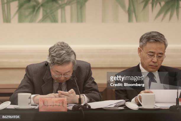 Zhou Xiaochuan, governor of the People's Bank of China , left, looks at his smart phone, as Guo Shuqing, chairman of the China Banking Regulatory...
