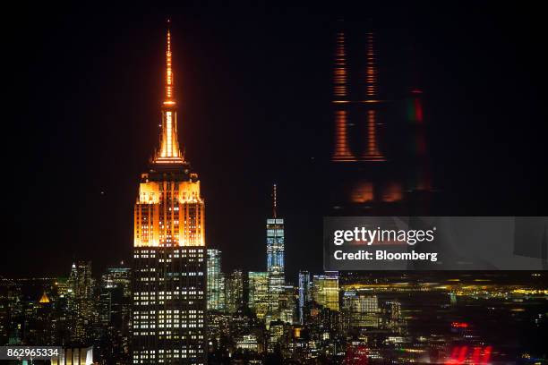 The spires of the Empire State Building, left, and One World Trade Center, center, stand lit in orange to support a bid for Amazon.com Inc.'s second...