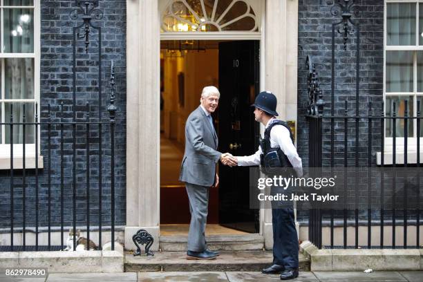 Former US President Bill Clinton shakes hands with a police officer as he arrives at Number 10 Downing Street on October 19, 2017 in London, England....