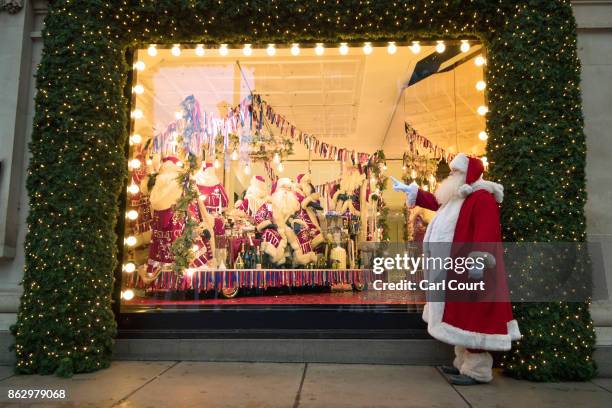 An actor dressed as Santa poses for photographs next to a Christmas window display at Selfridges on October 19, 2017 in London, England. Selfridges...