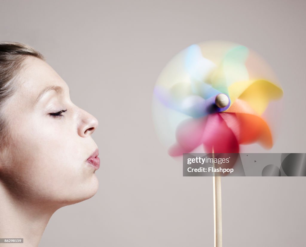 Close-up of woman blowing onto a windmill