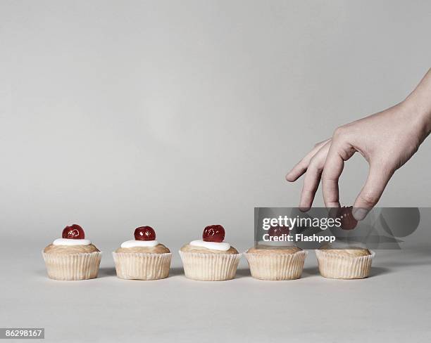 hand putting cherry on a cake - five objects stockfoto's en -beelden