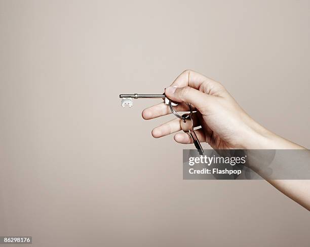 close-up of hand holding keys - sleutel beveiligingsapparatuur stockfoto's en -beelden