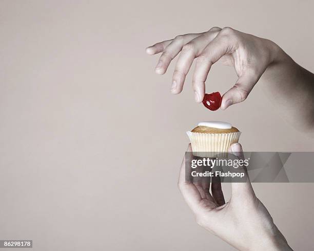 hand placing cherry on top of cup cake - interior finishing stock pictures, royalty-free photos & images