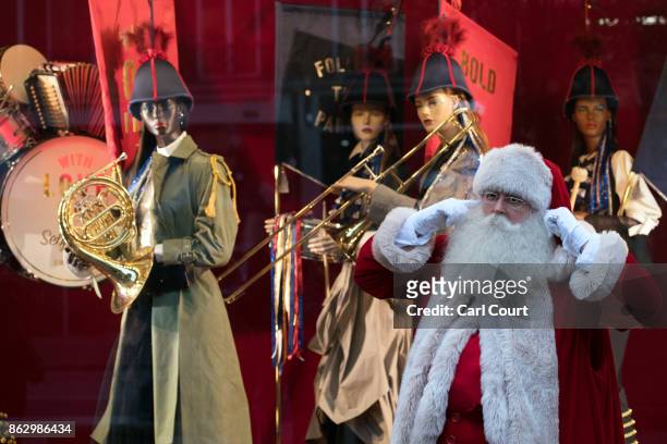 An actor dressed as Santa poses for photographs next to a Christmas window display at Selfridges on October 19, 2017 in London, England. Selfridges...