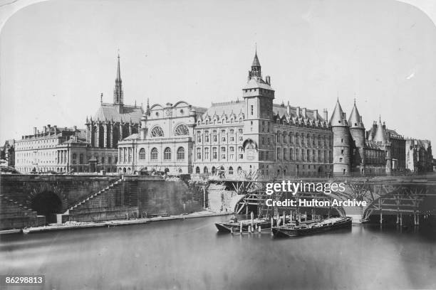 The Palais de Justice or law courts, and the Conciergerie prison on the Ile de la Cite in Paris, 1856. The Pont au Change is under construction on...