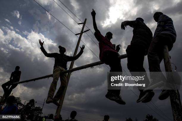 Supporters react as they sit on the crossbar of a goalpost during a National Super Alliance political rally in Nairobi, Kenya, on Wednesday, Oct. 18,...