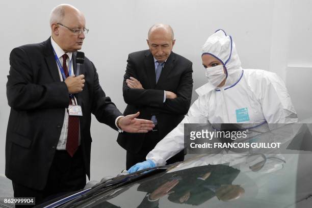 French Interior Minister Gerard Collomb listens to Xavier Espinasse , head of the regional forensic identification service, as he visits the...