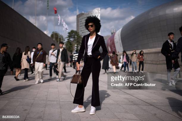 An attendee poses for a photo during Seoul Fashion Week at Dongdaemun Design Plaza in Seoul on October 19, 2017. For Seoul's flamboyant followers of...