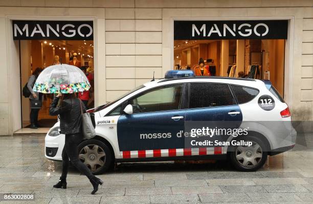 Woman walks past a patrol car of the Mossos d'Esquadra, the Catalonian regional police force, on October 19, 2017 in Barcelona, Spain. Catalonia's...