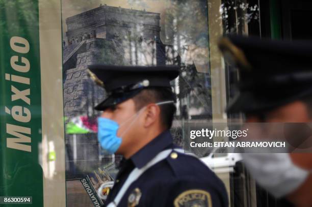 Policemen wearing face masks to prevent contagion by the swine flu virus, walk in front of a travel agency in Mexico City on April 30, 2009.The World...