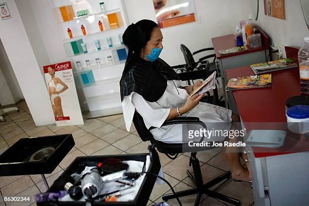 Customer waits for her beautician while wearing a surgical mask, to prevent becoming contaminated with swine flu, as the government advised people to...