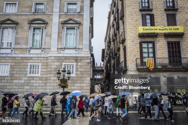 Tourists walk in the rain across Sant Jaume square, past the Generalitat regional government offices in Barcelona, Spain, on Thursday, Oct. 19, 2017....