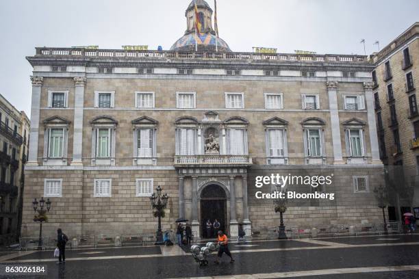 Worker pushes a trolley of barrels across Sant Jaume square past the front of the Generalitat regional government offices in Barcelona, Spain, on...