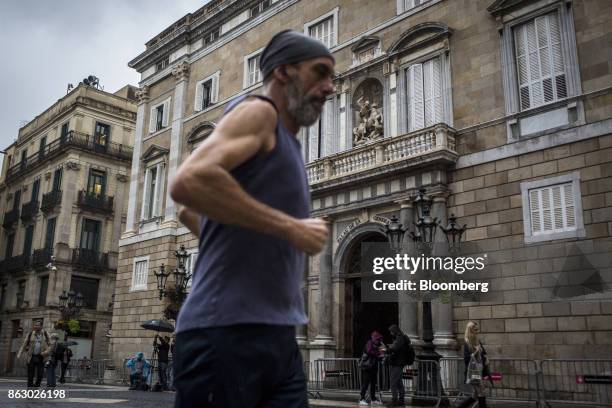 Man jogs past the entrance to the Generalitat regional government offices on Sant Jaume square in Barcelona, Spain, on Thursday, Oct. 19, 2017....