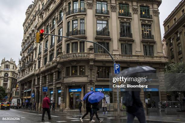 Pedestrians walk in the rain past a Banco de Sabadell SA bank branch on Via Laietana in Barcelona, Spain, on Thursday, Oct. 19, 2017. Spains...