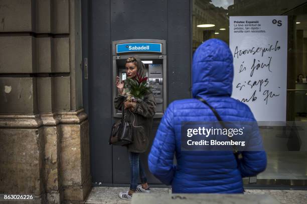 Customer pauses while using an automated teller machine outside a Banco de Sabadell SA bank branch in Barcelona, Spain, on Thursday, Oct. 19, 2017....