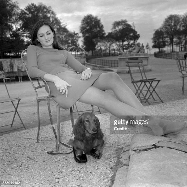 Une jeune femme et son chien, ses pattes dans les chaussures de la fille, se reposent le 23 octobre 1967 dans le jardin des Tuileries à Paris. AFP...