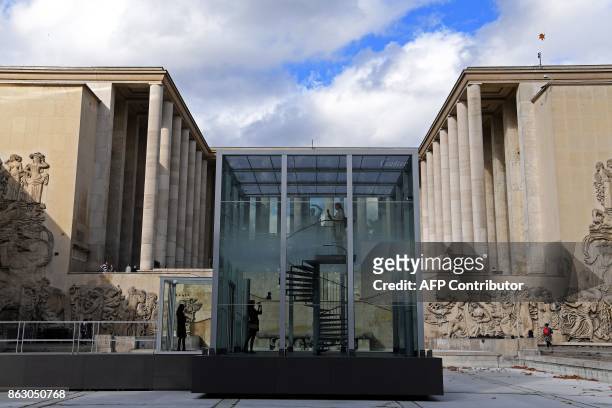 Person stands in a glass cube containing an olfactory cloud - Le Nuage Parfumé or OSNI 1 - launched by Cartier and displayed outside the Palais de...