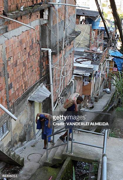 Workers carry portland cement sacks to the upper area of the Favela Santa Marta where a 634 m long wall surrounding the shantytown is being built, in...