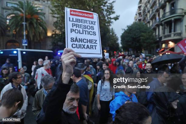 Protesters, including one holding a sign demanding the release of Catalonian independence leaders Jordi Sanchez and Jordi Cuixart, gather in between...