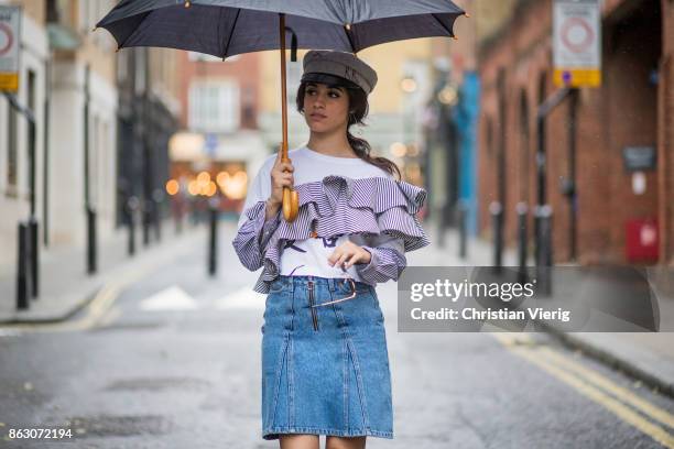 Camila Cabello wearing denim skirt Holzweiler, Dry Clean Only top, military hat Ruslan Baginskiy, Gianvito Rossi pumps is seen on October 19, 2017 in...