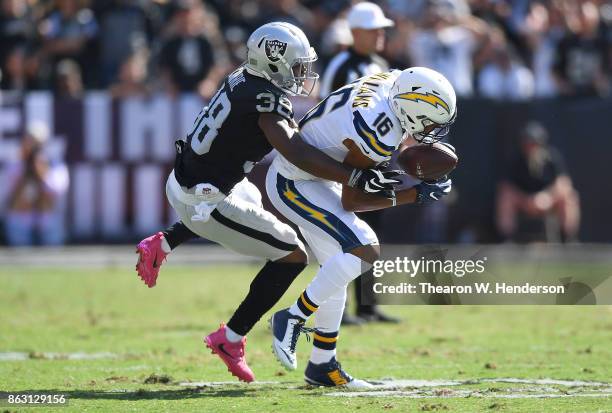 Tyrell Williams of the Los Angeles Chargers catches a pass and gets tackled by T.J. Carrie of the Oakland Raiders during an NFL football game at...